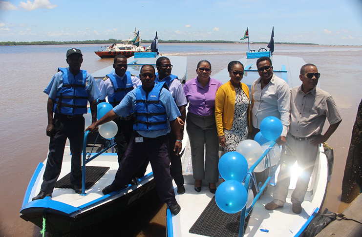 Officials from the Ministry of Public Infrastructure and Regional Democratic Council take photographs near the new vessels