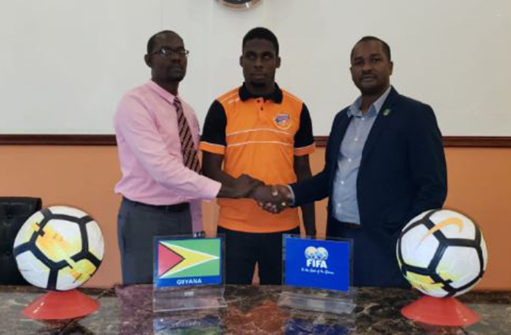 GOOD LUCK! Jeremy Garrett, flanked by GFF president Wayne Forde (first right) and secretary of the Fruta Conquerors football club. (Rawle Toney photo)
