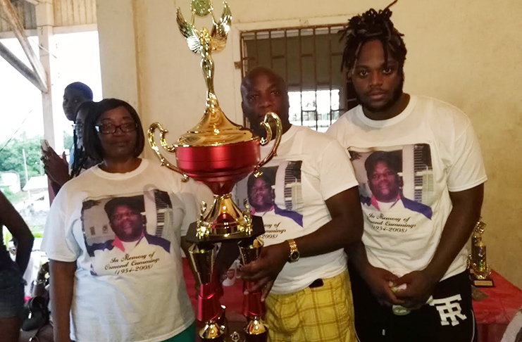 One year ago, former national striker US-based Nigel 'Mice' Cummings (centre) displayed the Osmond Cummings Memorial football trophy which is at stake in this evening's Under-20 championship final.