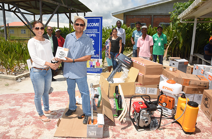 A representative of PROPEL (left) hands over the items to General Manager of Hope Coconut Industries Limited as farmers from the Hope Estate observe (Samuel Maughn photo)