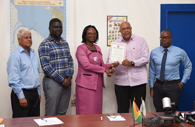 GNBS Head, Conformity Department Rodlyn Semple as she hands over the certificate and terms of conditions for the laboratory certification to GWI’s Managing-Director Dr. Richard Van-West Charles.