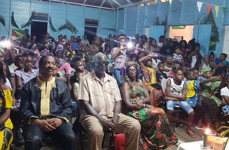 Attorney General and Minister of Legal Affairs Basil Williams sitting among residents of Bagotville on the eve of Emancipation Day