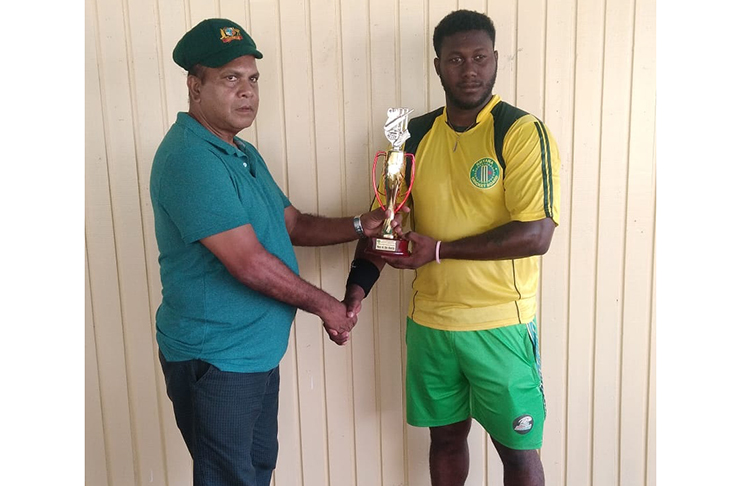 Ricardo Adams, man-of-the-match is presented with his trophy by match referee Moses Ramnarine.