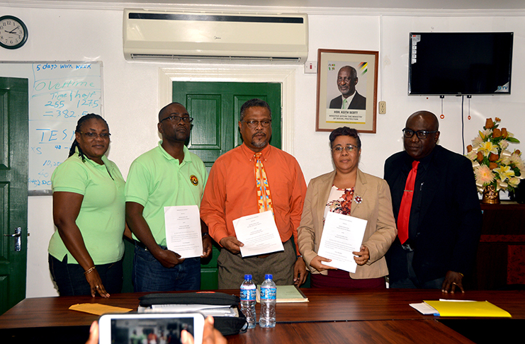 GTU and MoE representatives displaying a copy of the terms of resumption agreement at the Department of Labour Boardroom. From left are GTU General Secretary, Coretta McDonald; GTU President, Mark Lyte; Chief Labour Officer, Charles Ogle; Acting Permanent Secretary, Adele Clarke; and Chief Education Officer, Marcel Hutson (Adrian Narine photo)