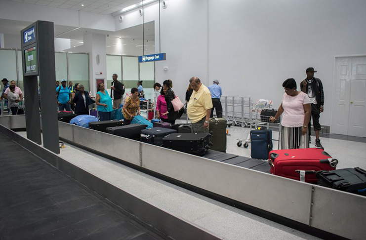 Passengers retrieve their luggage at the new arrivals terminal at the CJIA