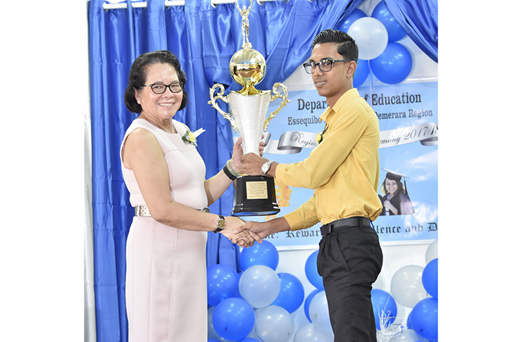 First Lady Sandra Granger presents a trophy to the West Demerara Secondary School CSEC top performer Setram Mohamed