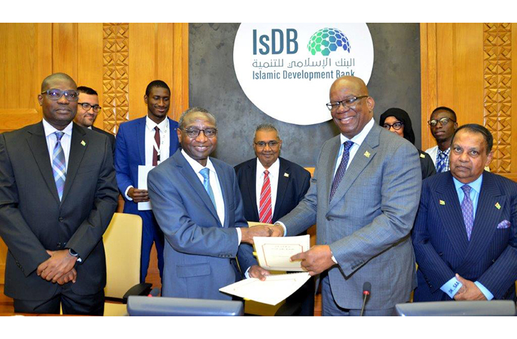 Finance Minister Winston Jordan exchanges documents following the signing of the loan agreement. Also in picture are Minister of Public Infrastructure David Patterson and Guyana’s Ambassador to Kuwait, Shamir Ally