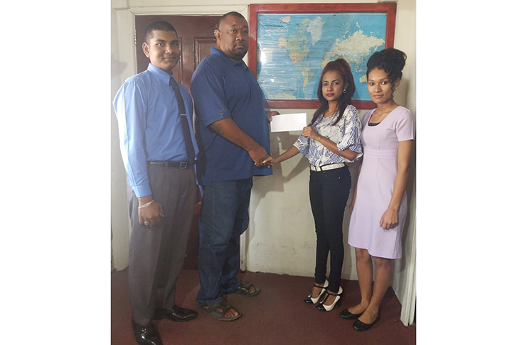 BCB president Hilbert Foster receives the sponsorship cheque from Amanda Budhoo in the presence of other staff members.