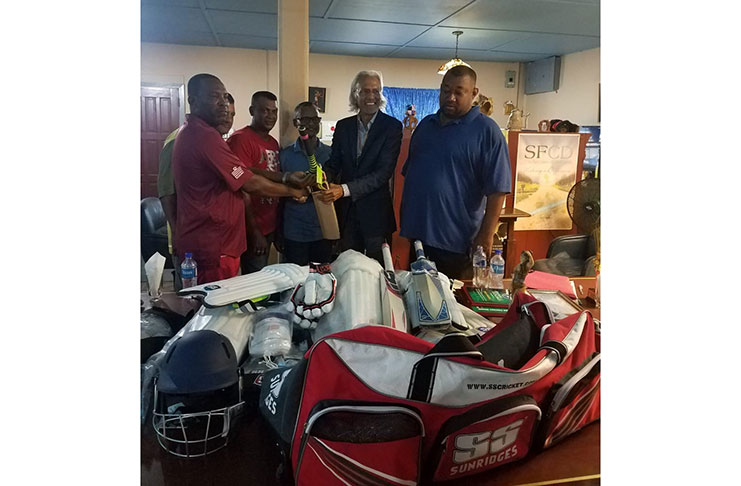 Brian Ramphal hands over gear to BCB senior coach Winston Smith in the presence of the other donors and BCB president Hilbert Foster.