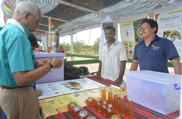 President David Granger assesses the quality of a bottle of honey produced by the Rupununi Friendly Beekeepers