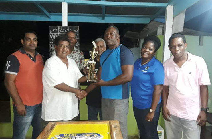 Manniram Shew (left) presents the winners’ trophy to Barbados’ Anderson Layne. Next to Layne is Charmaine Durant, vice-president of the Barbados Dominoes Association.