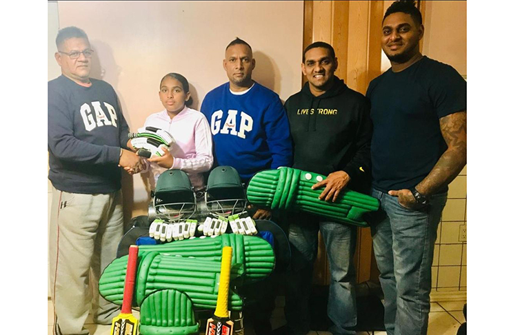 Rovendra Mandolall’s daughter Ronesha hands over the cricket gear to Gangadeen Lall. Others in picture (from left) are Rovendra and his siblings Ravendra and Narindra.