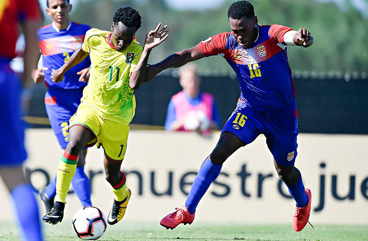 Kelsey Benjamin makes his way around Cayman Islands captain Eric Wilson during Guyana’s 3-2 defeat at the CONCACAF U20 Championship.