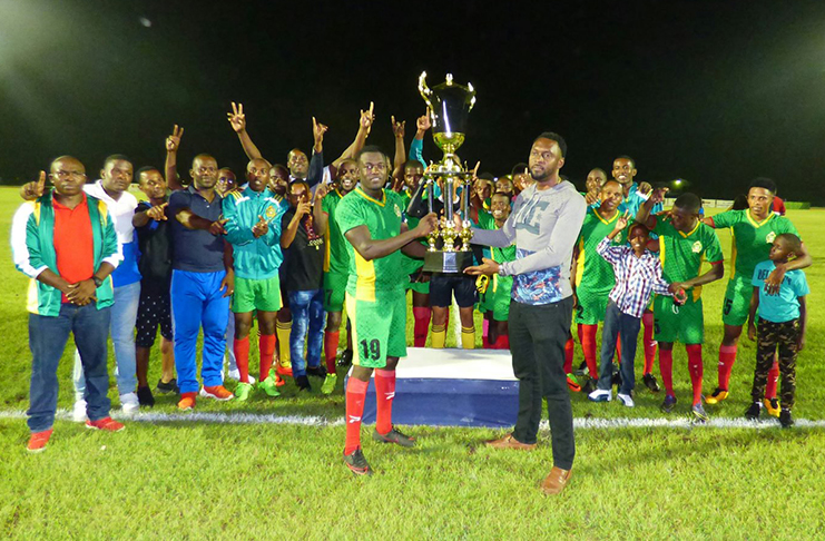 FLASHBACK! Director of Sport Christopher Jones handing over the championship trophy to the GDF captain in the presence of teammates and supporters, following their 2-0 win over Grove Hi-Tech in the Guyana Football Federation (GFF) ‘Super 16 Year-end Classic’ championship, at the National Track and Field Centre, Leonora. (Stabroek News photo)
