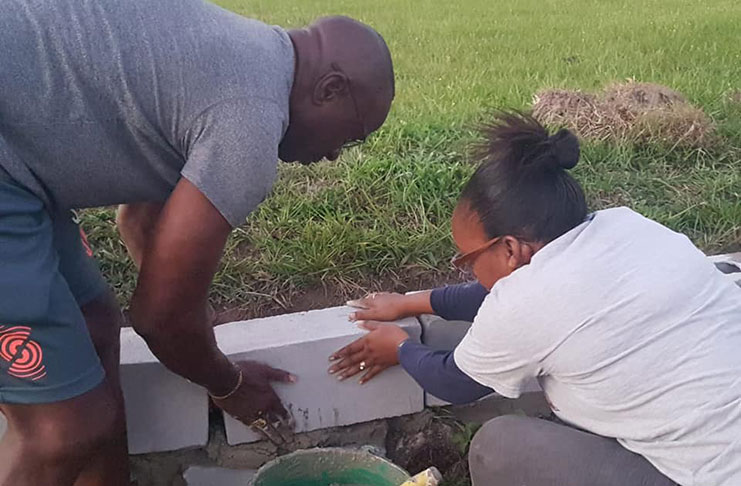 Linden Deputy Mayor Wainewright Bethune is hard at work. In this photo, he is seen installing a barrier in Richmond Hill with
the help of a member of the community policing group (Venessa Braithwaite)