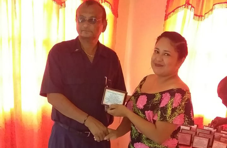 Prime Minister’s representative in Region Two,  Karran Chand, presenting one of the plaques to Anasa Federicks, a youth volunteer from Capoey