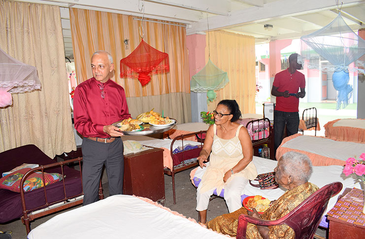 Minister of Communities Ronald Bulkan serving an elderly woman at the Dharm Shala Christmas Day luncheon
