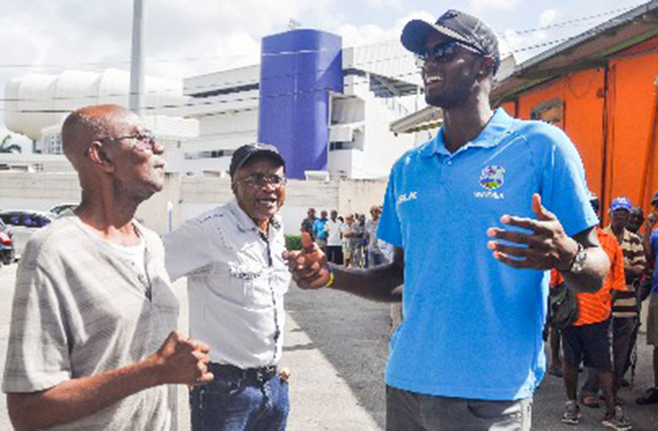 West Indies Test captain Jason Holder (right) has the attention of a few fans at the Kensington Oval ticket office.