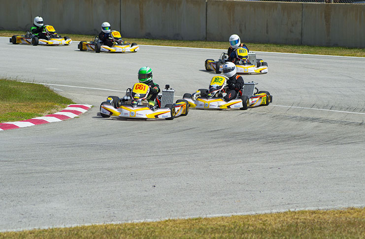 Jeremy Ten-Pow (61) goes into the first corner of the Bushy Park go-kart track, ahead of Jamaica’s Ryan Chisholm (J82) and Barbados Kayleigh Catwell (B07). In the background is Rayden Persaud (G26) and Zachary Persaud (G79). (Stephan Sookram/GFXRacing photo)
