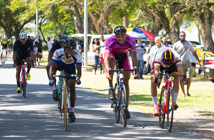 Balram Narine (left) powers over the finish line ahead of Paul DeNobrega (right) and Michael Anthony (centre) to cop the feature event of the 26th Ricks & Sari Cycling meet. (Delano Williams photo)