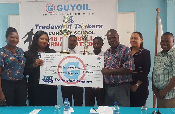 From left, Petra’s Jacquline Boodie watches as GUYOIL Marketing and Sales Manager Jacqueline James hands over the winners’ cheque and trophies to Annandale Secondary School for their win in the inaugural GUYOIL/Tradewind Tankers Schools Football League. (Stephan Sookram photo)