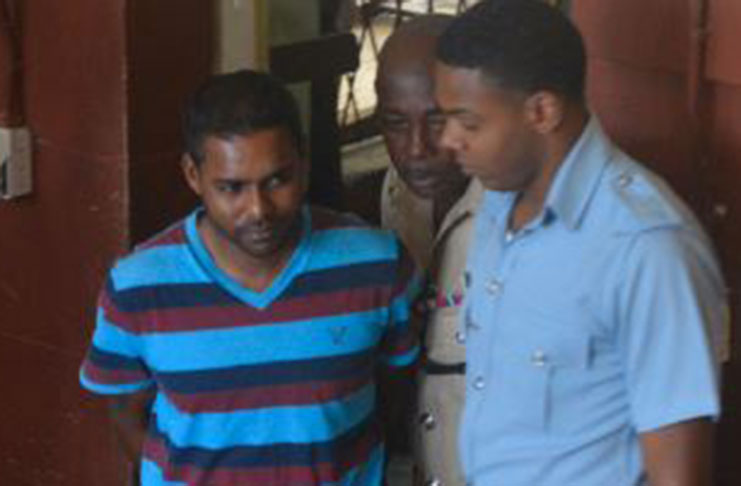 Assistant Superintendent, Seecharran Singh (in stripe top) being led to the courtroom by police ranks