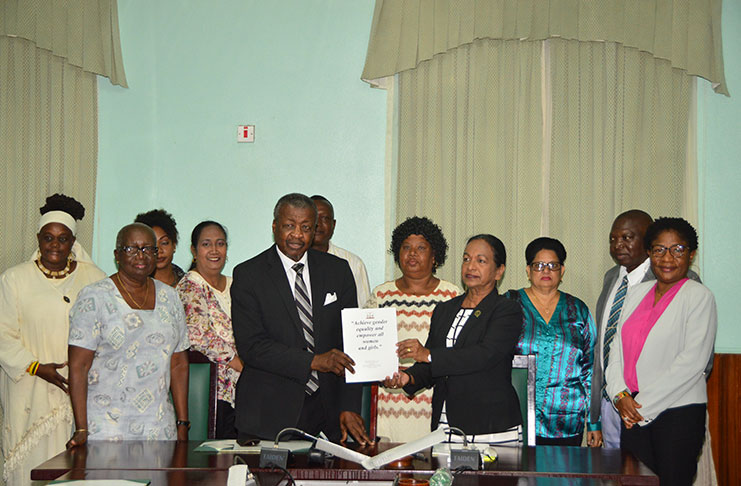 Speaker of the National Assembly, Dr. Barton Scotland receiving the report from WGEC Chairperson Indranie Chandarpal. Surrounding them are other members of the commission and Clerk of the National Assembly, Sherlock Isaacs (second right)