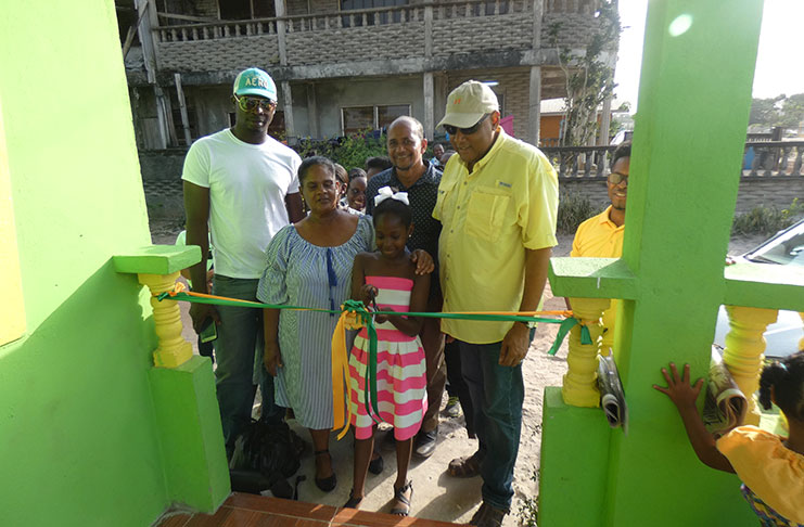 June Allicock (right), assisting the youngest grandaughter in her care to cut the ceremonial ribbon while Minister Raphael Trotman (left) and other AFC executives look on