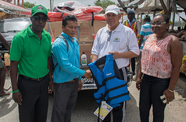 Social Cohesion Minister, Dr. George Norton, hands over one of the life jackets to toshao of Akawini, David Williams