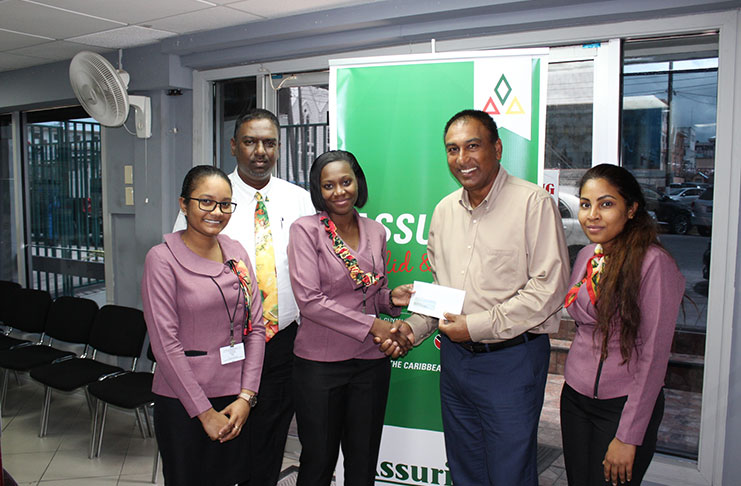 Assuria General Manager Yogindra Arjune (second from left) watches as one of the staff members hands over the company’s sponsorship to LGC president Aleem Hussain.
