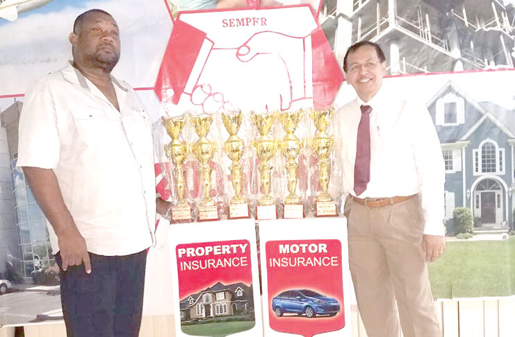 Mr Howard Cox of Hand-in-Hand hands over trophies to CEO Hilbert Foster.