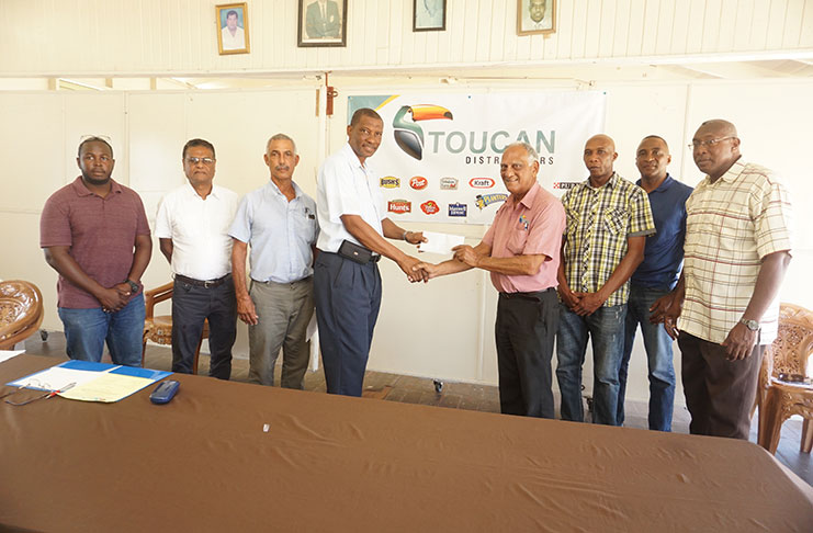 GCA president Roger Harper (right) collects the sponsorship from Toucan Distributors’ Lenny Shuffler for the GCA U-15 league. In the background are GCA executives along with Managing Director of Toucan Distributors Andrew King. (Carl Croker photo)