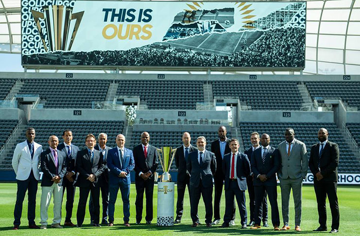 Head coaches from the 16 participating teams pose with the 2019 CONCACAF Gold Cup trophy.