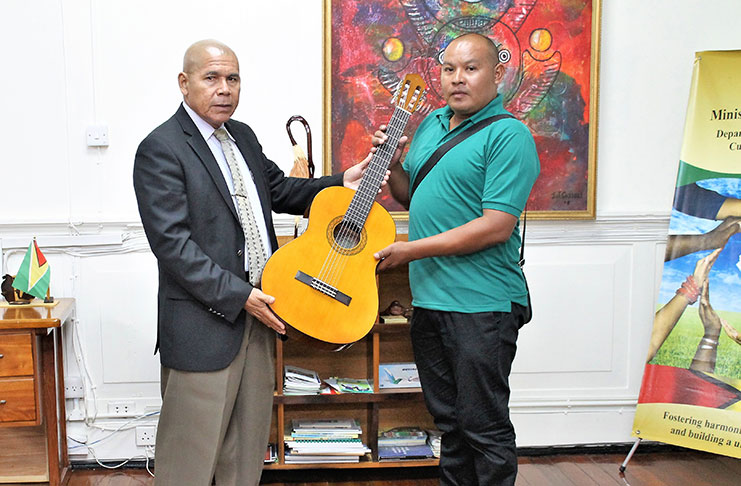 Minister Norton presenting the brand new guitar to Mr. Ishmael Abrams, a Councillor attached to the Regional Democratic Council of Region Seven