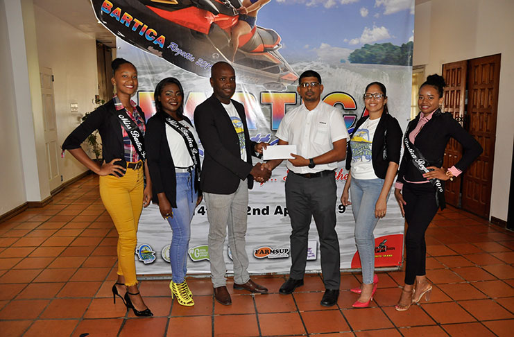 Accounts Manager, Harold Babulall, hands over sponsorship cheque to Mayor Gifford Marshall in the presence pf Regatta Committee Organising Secretary Ciana Persaud (2nd right) and some of the Pageant contestants.