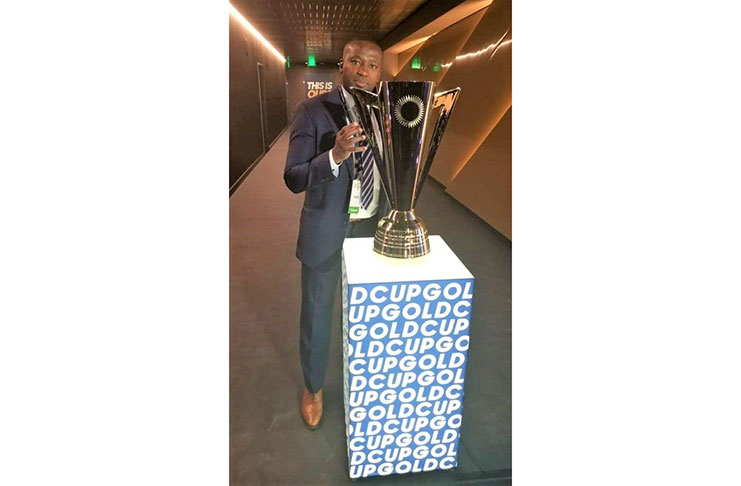 Seeing into the future? Guyana’s head coach Michael Johnson shares a moment with the CONCACAF Gold Cup trophy.