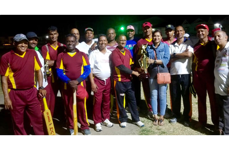 A smiling Kenrick Persaud, captain of Parika Defenders, receives the winners’ trophy from Devi Sunich, wife of Ramesh Sunich in the presence of his teammates and Ramchand Ragbeer, president of GFSCA.