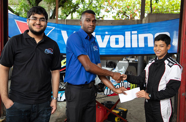 Nathan Rahaman is all smiles as he collects sponsorship from Sankar’s Auto Works representative Keon Joseph in the presence of Navin Sankar.