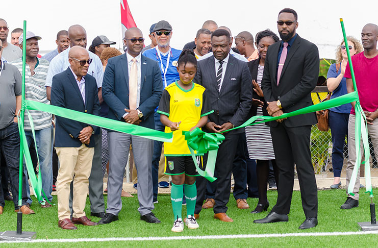 Fruta Conquerors and National midfielder, 15-year-old Alleia Alleyne, cuts the ‘symbolic ribbon’ to commission the football pitch at the FIFA Forward Project. Also in photo (Standing in the forefront from left), CFU president Randy Harris, GFF president Wayne Forde, FIFA’s Director of Member Associations and Development Veron Mosgengo-Omba and Director of Sport Christopher Jones. (Delano Williams photo)