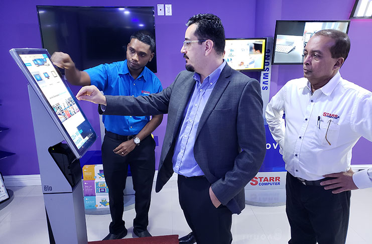 Regional Sales Director for Elo Touch, Carlos Corredor, shows 
President of STARR Computer, Mike Mohan, and Manager, Raydon Samaroo, ways in which consumers can use the rugged Kiosk to enhance business