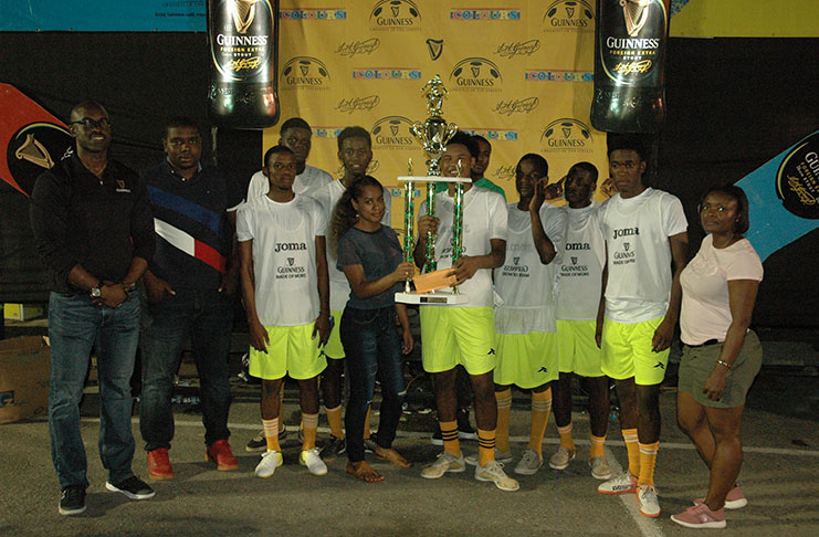 High Rollers captain, Omar Brewley (centre), collects the championship trophy from Banks DIH representative Romaine Adonis in the presence of his team-mates, while Guinness Brand Manager Lee Baptiste (left) and other officials look on.