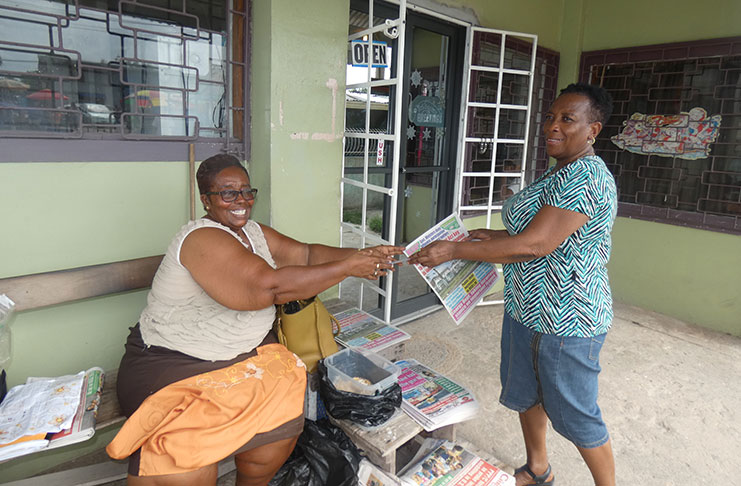 Newspaper vendor Joycelyn Benjamin selling her newspaper to a customer