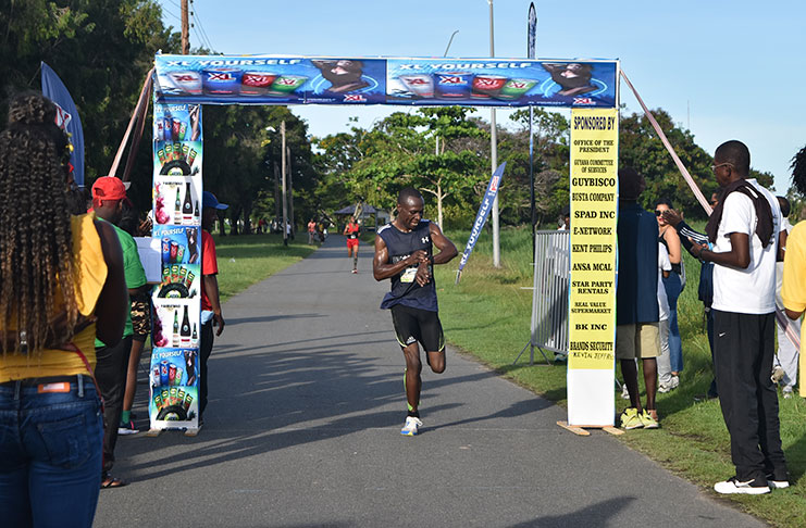 Kenyan Godfrey Mbihia crosses the finish line to capture the GCOS 5K on Monday afternoon.