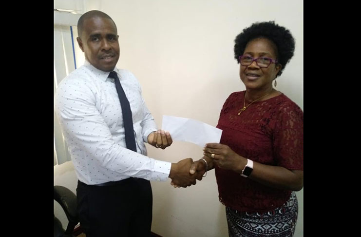 At left is Aaron Fraser, CEO of the Guyana Power Producing and Distribution Inc., as he hands over cheque to Ms Haley Rutherford.