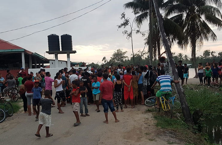 Residents gather at the alleged murder scene to get a glimpse of Eon Williams’s body.