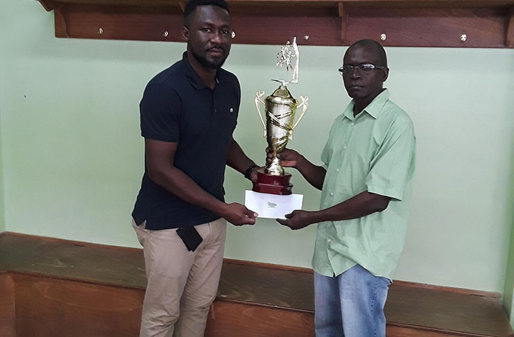 Chris Bowman (left) is seen handing over the winners’ trophy and cheque to Joseph Chapman for the Linden YBG basketball championship.