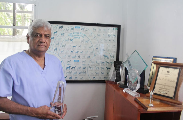Dr. Steve Surujbally holds the award he received from the Caribbean Veterinary Medical Association, alongside his other accolades