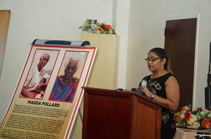 A family member of deceased honouree Magda Pollard delivers a tribute, as a portrait of Pollard with a citation is displayed at left.