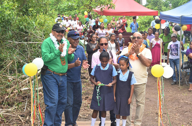 Minister of Indigenous Peoples' Affairs, Sydney Allicock (left)  and other officials applaud as a child from the village cuts the ribbon which officially marks the commissioning of the new structure. (MOIPA photo)