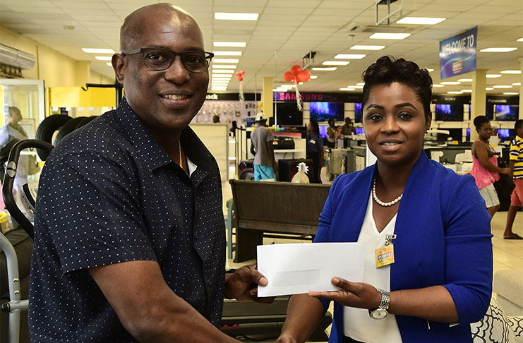 GBA president Steve Ninvalle (left) receives a cheque for an undisclosed sum from COURTS Brand Manager, Odetta Aaron. (Adrian Narine photo)